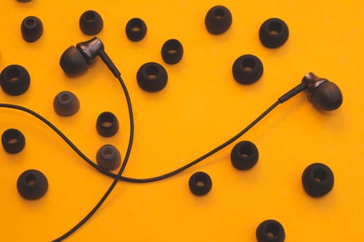 Earphones between of ear cushions on yellow background. in-ear headphones with many embouchures. modern style. audio equipment