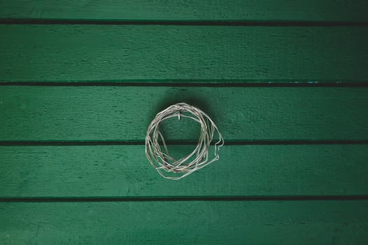 Coil of wire hanging on the green painted wooden wall