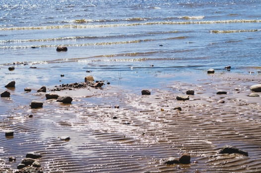 Stones on wavy wet sand. pebbles on the seashore close up. abstract background