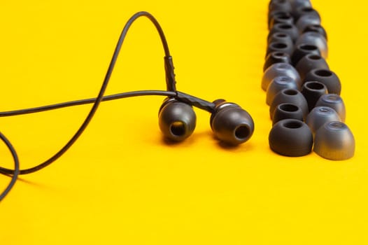 Earphones between of ear cushions on yellow background. in-ear headphones with many embouchures. modern style. audio equipment