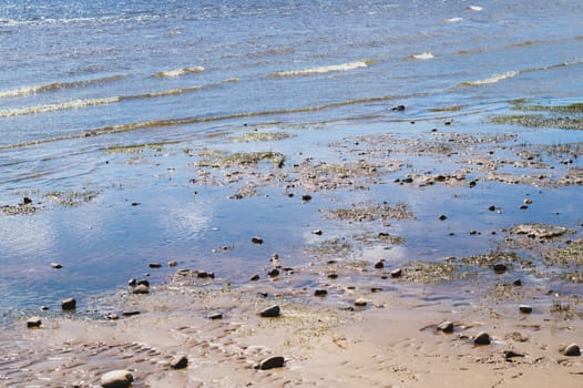 Stones on wavy wet sand. pebbles on the seashore close up. abstract background