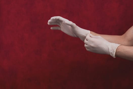 Hands in medical gloves on a red background. a person puts on surgical gloves