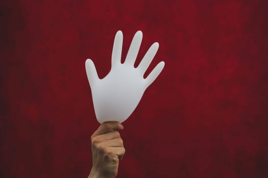 Hand holds inflated surgical glove on a red background