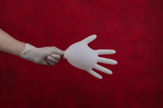 Hand holds inflated medical glove on a red background