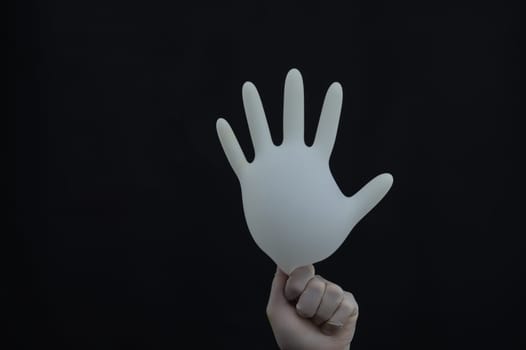 Hand holds inflated medical glove on a black background