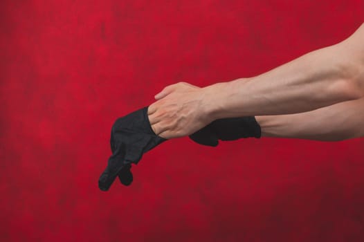 Hands in black medical gloves. person puts on surgical gloves on a red background