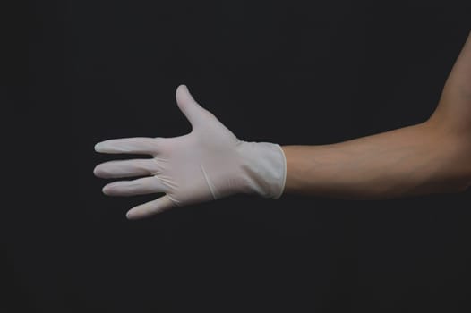 Hand in medical glove reach out. gesturing hand in white protective glove on a black background