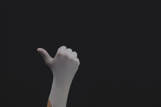 Hand in white medical glove shows thumbs up on a black background