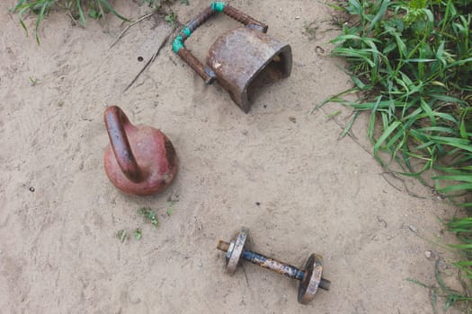 Kettlebells and dumbbell on the sand. handmade fitness equipment. weight lifting