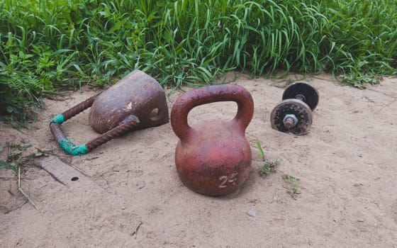 Kettlebells and dumbbell on the sand. handmade fitness equipment. weight lifting