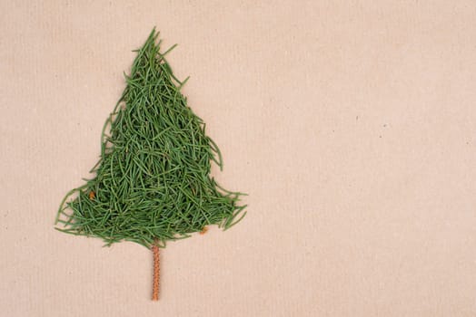 Christmas tree made from fir needles, brown colored paper, copy space, textured background, minimalism