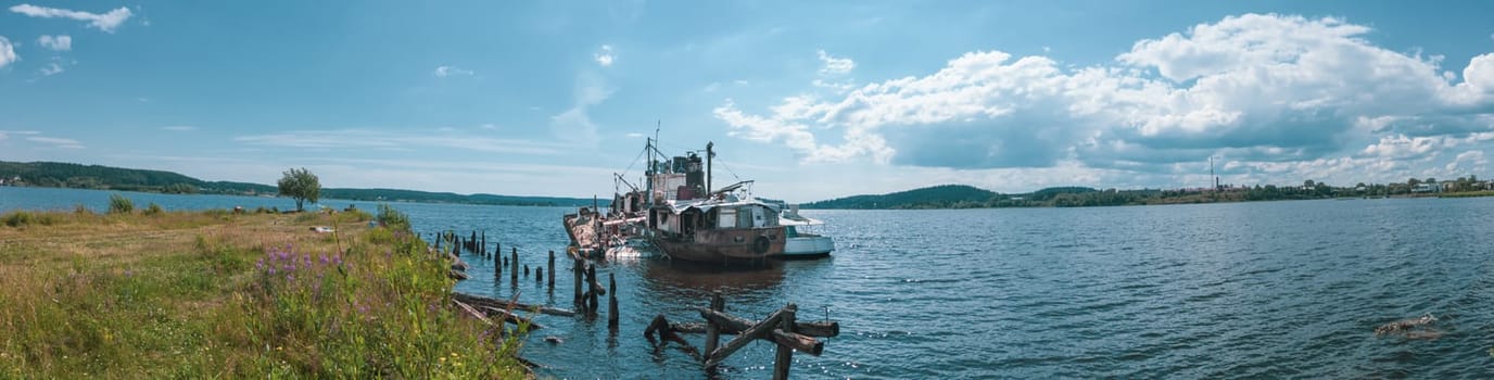 Abandoned ship in the bay on a summer day panorama. sunken boat