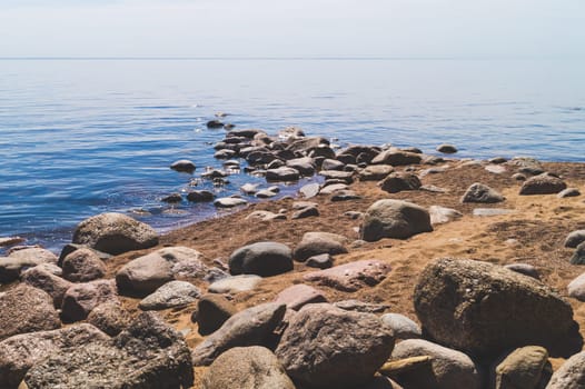 Path to the sea with stones on the sandy shore. summer landscape. horizon line