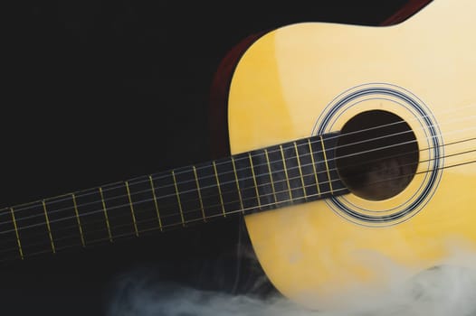 Guitar in smoke on the black background. acoustic musical instrument