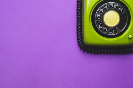 Vintage rotary phone. classic green telephone with round dial. isolated on purple background. old communication technology. copy space