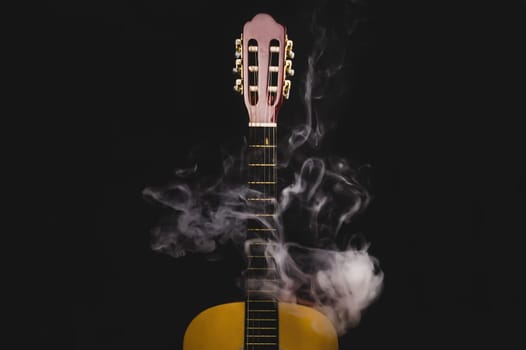Guitar in smoke on the black background. acoustic musical instrument. strings on the guitar neck