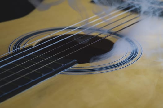 Guitar in smoke close up. acoustic musical instrument. strings on the guitar neck