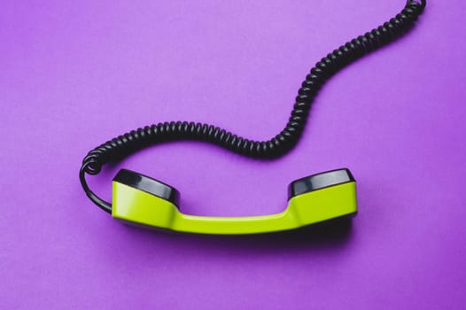 Vintage green telephone handset. phone receiver isolated on purple background. old communication technology. copy space