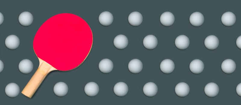Red table tennis racket with many balls arranged symmetrically on a colored background. sports equipment for ping pong