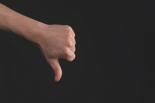 Thumbs down hand on black background. hand lowers big finger