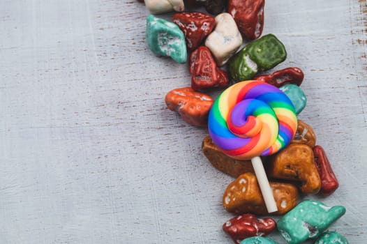 Festive decoration. lollipop and candy pebbles. sweets in the form of colored stones. white wooden background with colorful candies. copy space