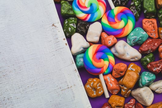 Lollipops and candy pebbles. sweets in the form of colored stones. colored background with colorful candies. festive decoration. copy space