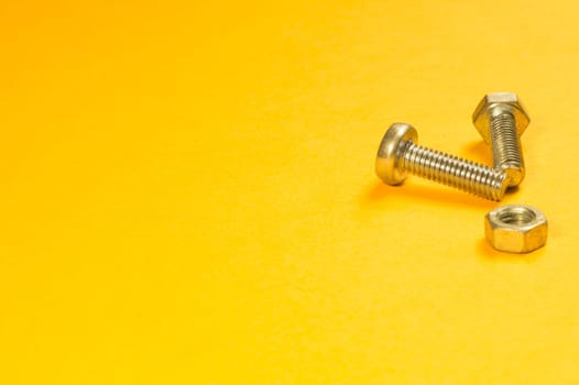 Steel screw on a yellow background. working tools
