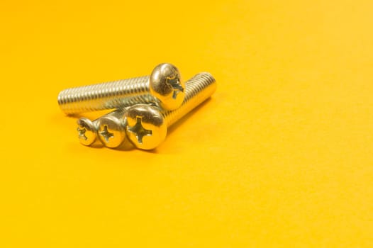 Steel screw on a yellow background. working tools