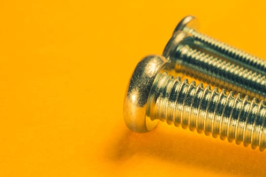 Steel screw on a yellow background. working tools