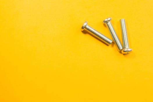Steel screw on a yellow background. working tools