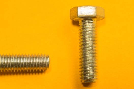 Steel screw on a yellow background. working tools