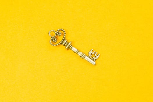 Old key isolated on yellow background. safety and security concept