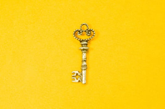 Old key isolated on yellow background. safety and security concept