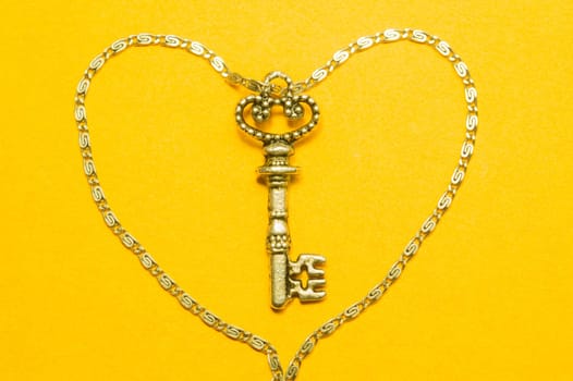 Old key with the chain isolated on yellow background. safety and security concept