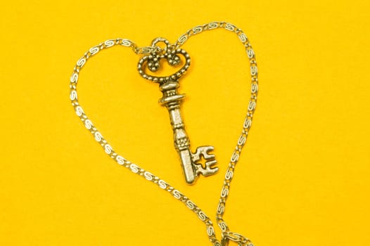 Old key with the chain isolated on yellow background. safety and security concept