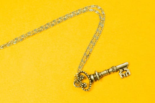 Old key with the chain isolated on yellow background. safety and security concept