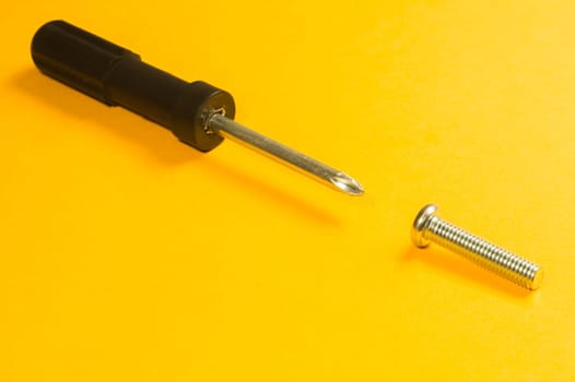 Steel screw on a yellow background. working tools