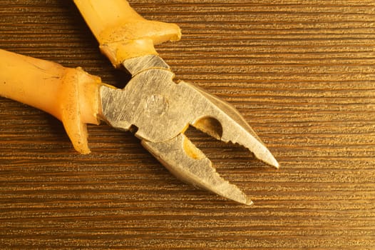 Pliers with orange handles on wooden background. work tool