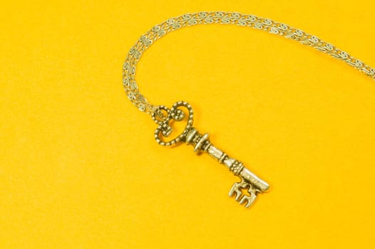 Old key with the chain isolated on yellow background. safety and security concept