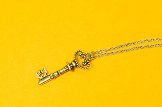 Old key with the chain isolated on yellow background. safety and security concept