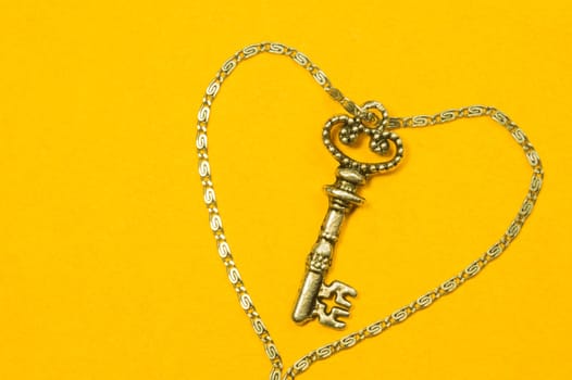 Old key with the chain isolated on yellow background. safety and security concept