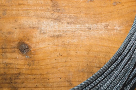 Steel cable on wooden background. hank of metal rope lies on the table. work tool