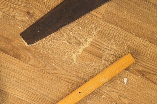 Old hand saw on a wooden background. working area with hand tool. carpentry instrument. manual labor concept