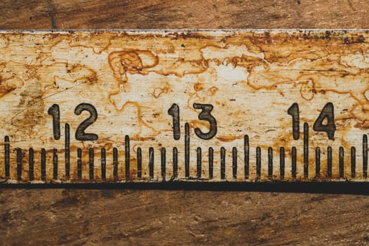 Old rusty ruler with black numbers on a working wooden table. vintage measuring tape close up. industrial background. carpentry workbench