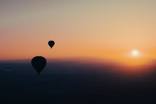 landscape with hot air balloons black silhouette rising up to the sky at sunrise with beautiful high mountain panorama in the background