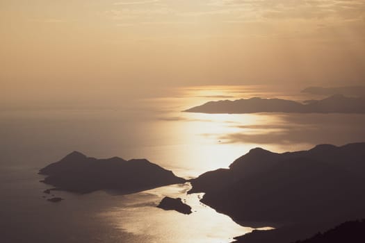 beautiful aerial panorama from the Babadag peak of high mountains rising up over the Mediterranean sea at sunset near Oludeniz Blue Lagoon coast in Turkey during summer