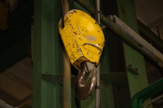 Yellow crane hook hanging in the factory. industrial background