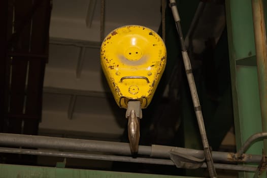 Yellow crane hook hanging in the factory. industrial background