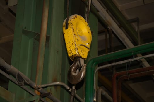 Yellow crane hook hanging in the factory. industrial background