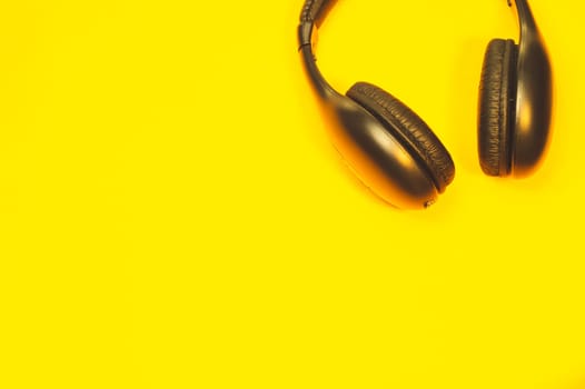 Black headphones on a yellow background. wireless earphones